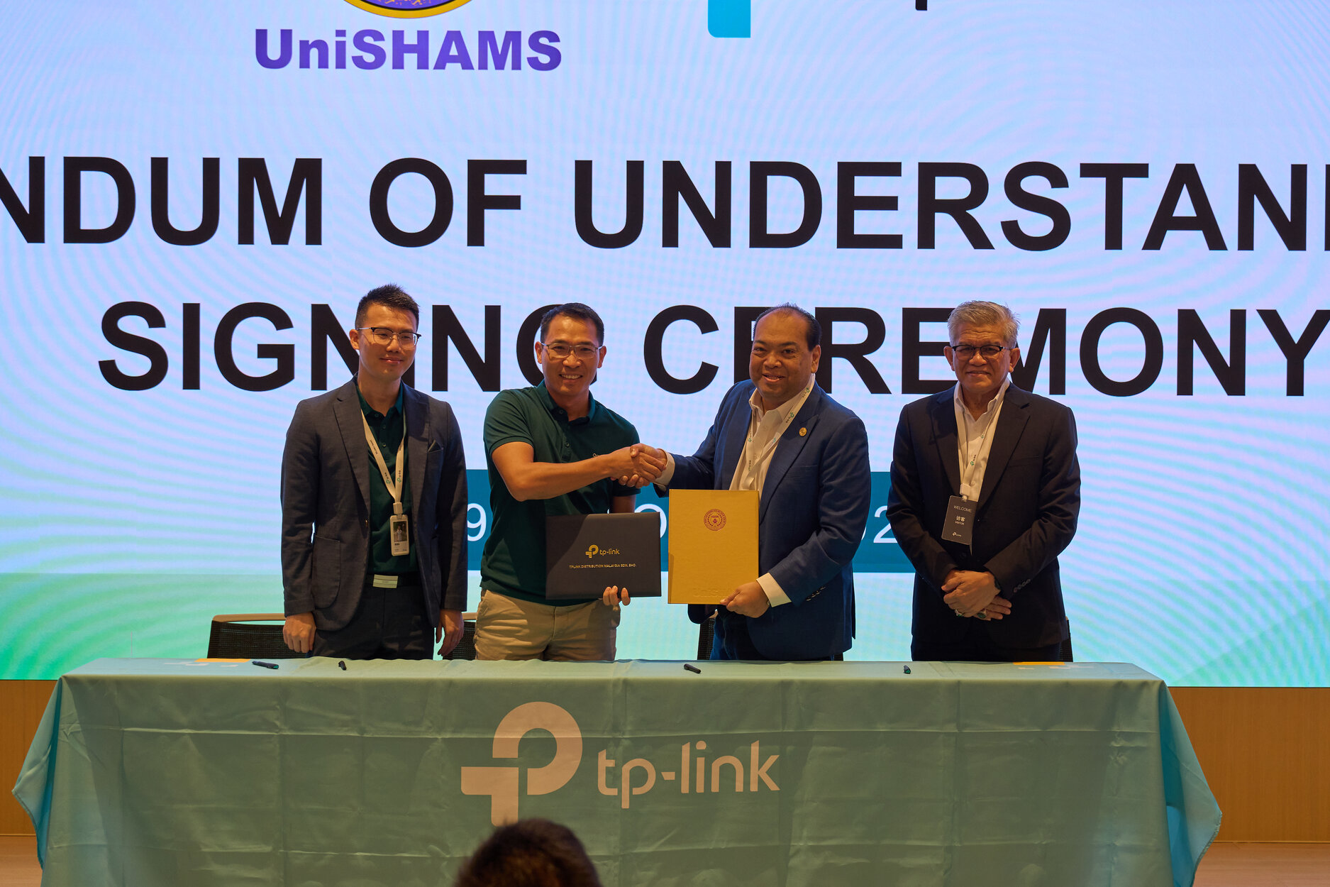 Naib Presiden TP-Link Asia Pasifik dan Naib Canselor UniSHAMS berjabat tangan selepas menandatangani dokumen MoU di atas pentas